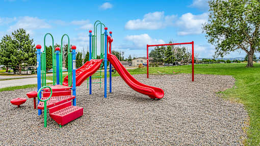 a playground with a red slide and monkey bars in a park