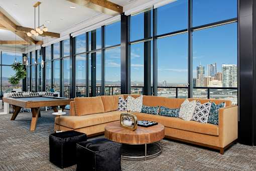 Sky lounge with sectional couch, pool table and large glass windows with view of Denver skyline