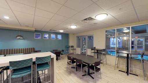 A room with tables and chairs and a pool table.