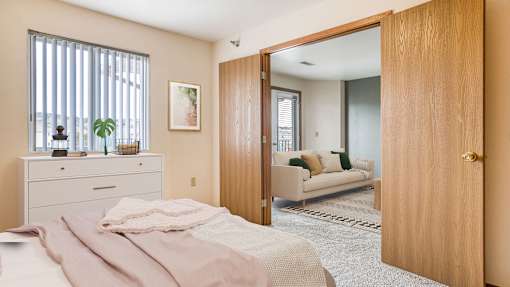 a bedroom with a bed and a door to a living room
