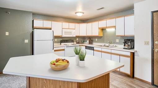 a kitchen with white cabinets and a bowl of fruit