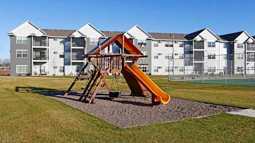 a playground with a slide in front of an apartment building