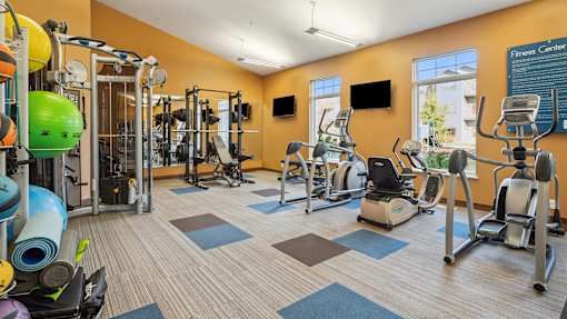 A gym with a variety of equipment including treadmills, weights, and exercise machines.
