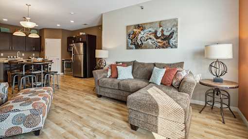 A living room with a grey couch and a painting on the wall.
