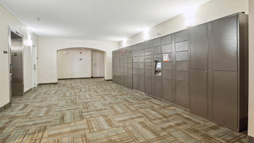 A long hallway with a carpeted floor and a wall of lockers on the right.