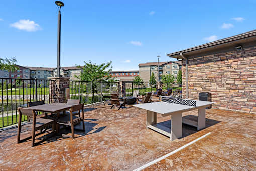 A patio with a table and chairs and a paddle ball table.