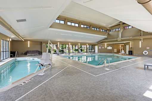 A large indoor swimming pool with a lounge chair.
