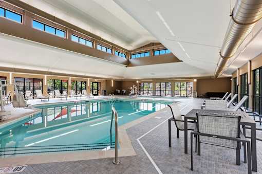 A large indoor swimming pool with lounge chairs and a metal pole.