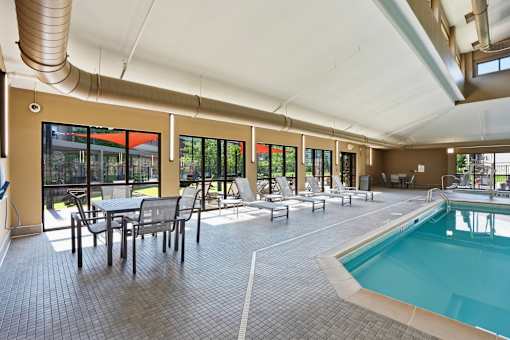A large indoor swimming pool with a table and chairs.