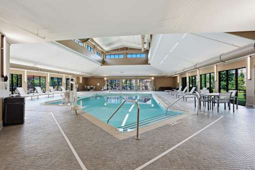 A large indoor swimming pool with a tiled floor and a ceiling with skylights.