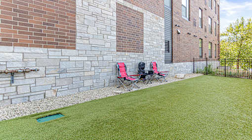 Two red chairs are placed on a green lawn.