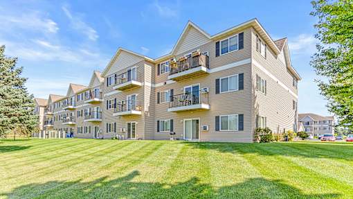a large apartment building with balconies and a lawn