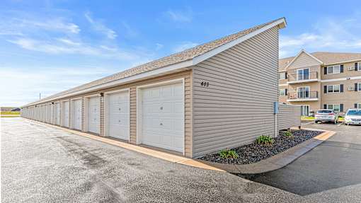 a small garage with white doors in front of an apartment building