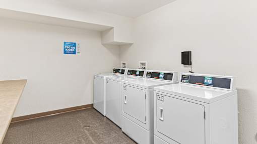 a laundry room with four washers and dryers and a table with laundry machines