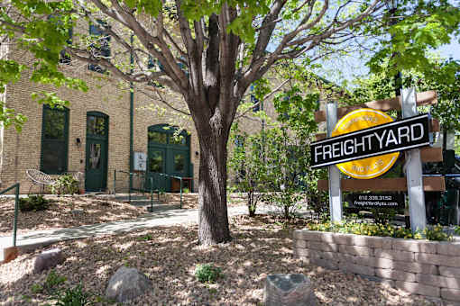 Angled image of FreightYard building exterior of exposed brick with large tree in front.
