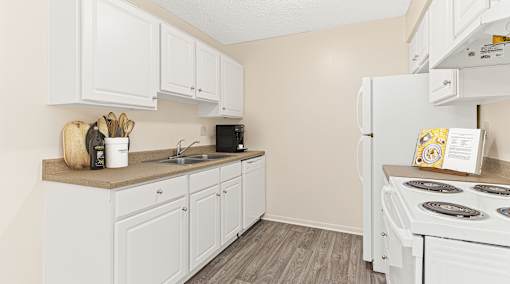 a kitchen with white cabinets and appliances and a white refrigerator