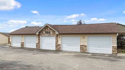 a brick garage with white doors and a sign on the roof
