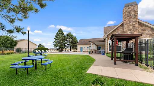 a patio with picnic tables and a pool in the backyard of a house