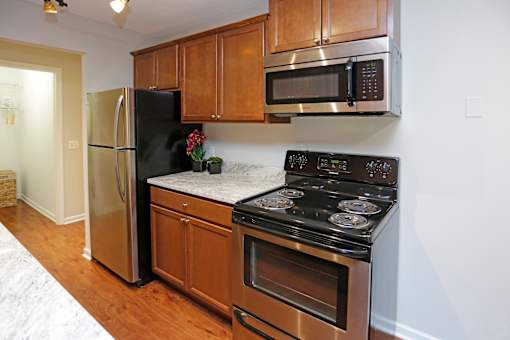 A kitchen with a black stove top oven and a black microwave above it.