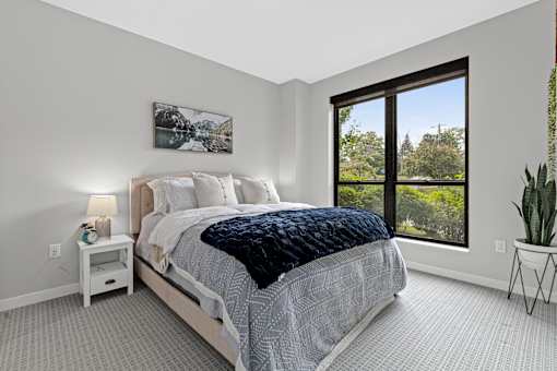 A bedroom with a large bed and a window overlooking a tree-filled landscape.