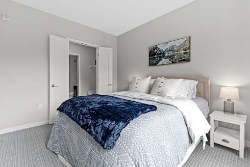 A bedroom with a large bed and a painting on the wall.