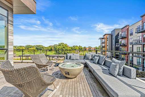 A patio with a hot tub and chairs overlooks a row of buildings.