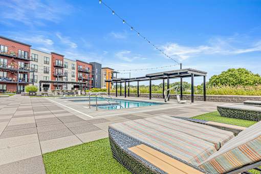 A pool area with a striped sun lounger and a building in the background.