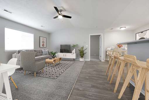 Wide view of living room filled with natural light from the large window above the gray couch.