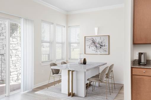 a dining room with a white table and chairs and a painting on the wall