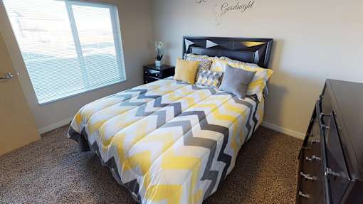 a bedroom with a yellow and gray comforter on a bed