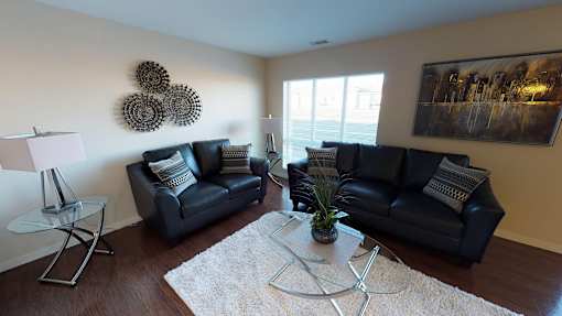 a living room with black leather furniture and a white rug