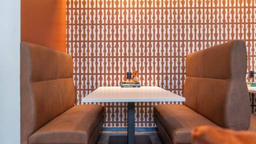 Two brown chairs are facing a white table with a book on it.