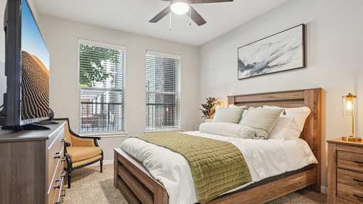 A bedroom with a bed, chair, and a television.