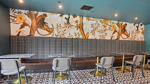A restaurant with a blue wall and a mural of a tree with birds on it.