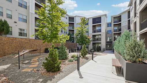A courtyard with a bench and a tree in front of apartment buildings.
