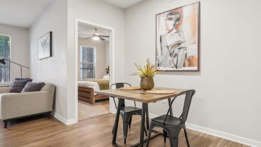 A dining room with a table, chairs and a painting on the wall.