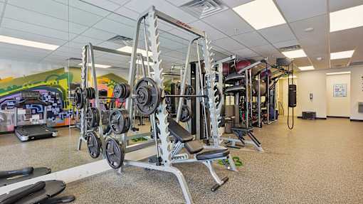 A gym with a variety of equipment including dumbbells and weight machines.
