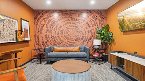 A living room with a couch, a chair, a table, and a plant.