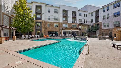A large swimming pool in front of apartment buildings.