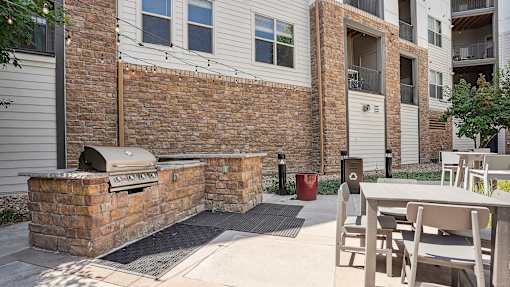 an outside patio with a grill and a table with chairs
