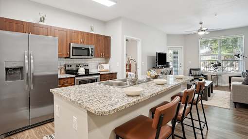 an open kitchen and living room with a granite counter top