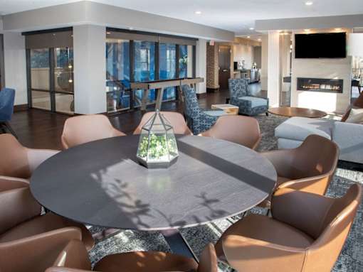 Community room with large circular table and many chairs, shuffleboard table