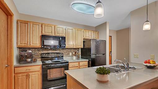 an updated kitchen with black appliances and wood cabinets