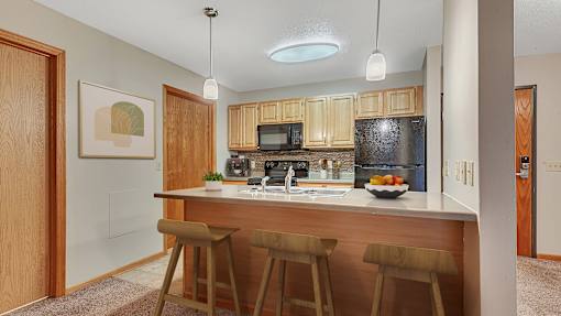 a kitchen with wooden cabinets and a counter with three bar stools