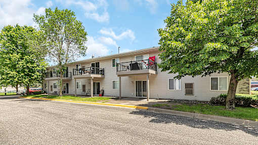 an apartment building with a street and trees in front of it