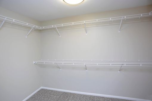 Inside of spacious walk in closet with plenty of shelves and hanging space.