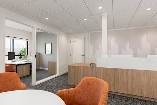 A white table is in the middle of a room with orange chairs.