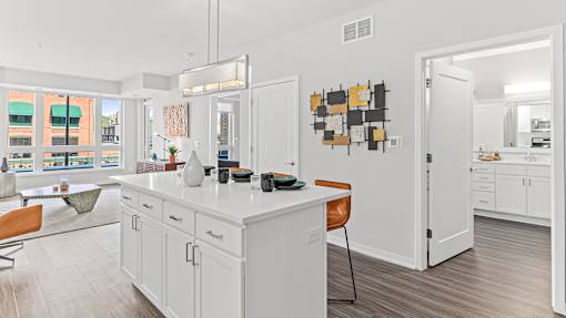 a kitchen with white cabinets and a white counter top and a door to a living