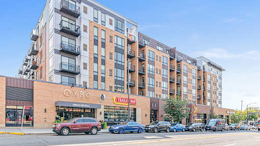 a city street with cars parked in front of an apartment building
