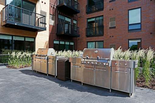 Outdoor grilling station with the exterior brick of Oxbo Urban Rentals behind.